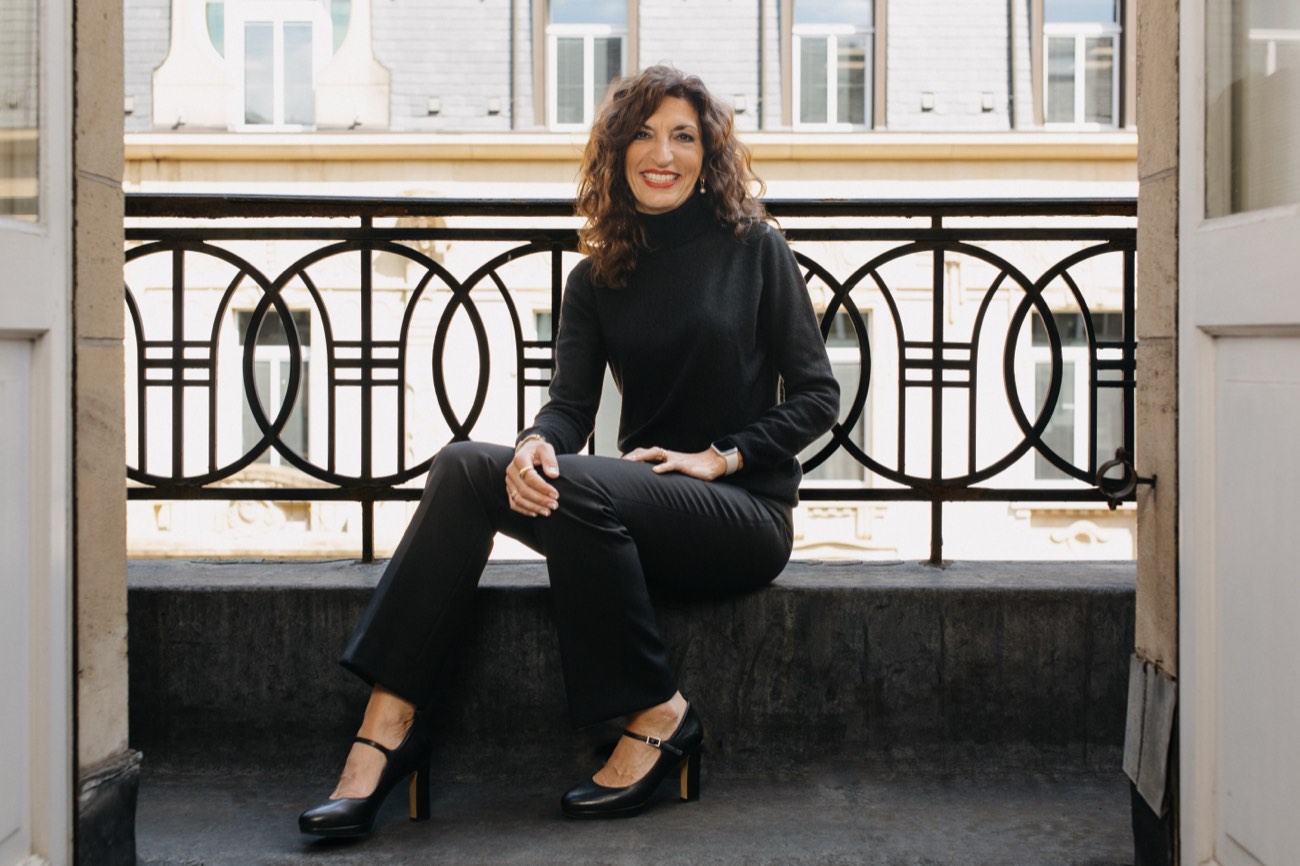 Charlotte Pedersen, founder of Pegasus Consilium, seated on a balcony ledge.